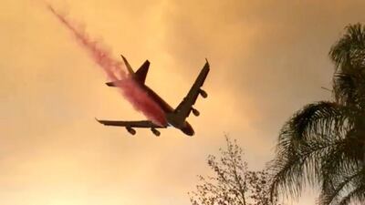 A plane dumps fire retardant over a fire as it spreads in Lake Elsinore, California on Wednesday, August 8. Reuters