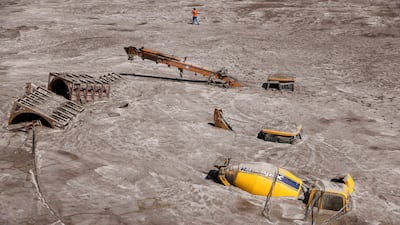 A man walks past construction vehicles submerged in debris caused by flash floods after a lake burst in Rangpo, India, in October. Reuters